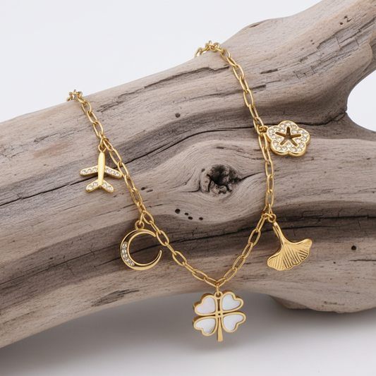 Esta pulseira em aço inoxidável delicada reúne os símbolos universais da proteção e da aventura: o trevo para a fortuna, o avião para as novas experiências e a lua para a intuição.