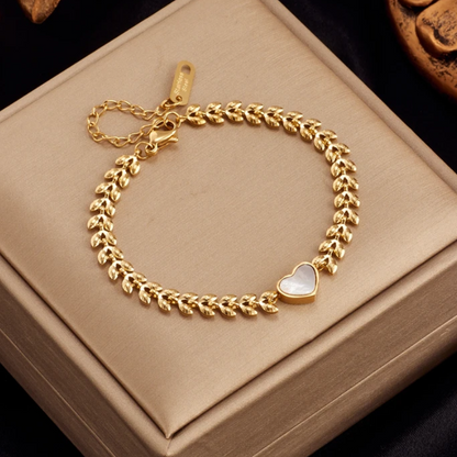 Esta pulseira destaca-se pela sua corrente artística composta por elos em forma de folhas detalhadas, que culminam num pendente central de coração em madrepérola natural.