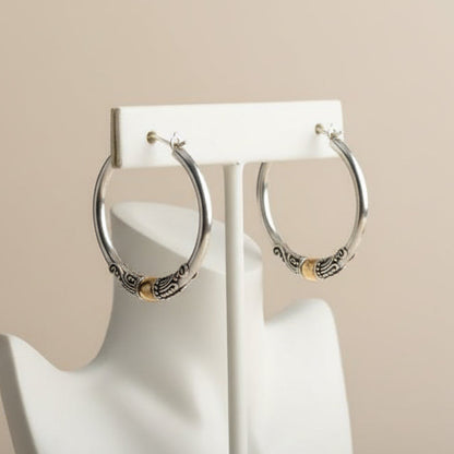 Estas argolas em Prata de Lei combinam o brilho do metal nobre com gravuras étnicas detalhadas. Uma peça statement que nunca sai de moda.
