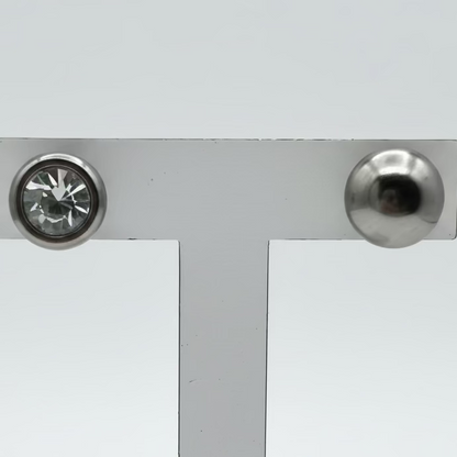 Estes brincos apresentam um cristal transparente embutido numa moldura de aço inoxidável, proporcionando um brilho clássico e sofisticado que combina com qualquer ocasião.
